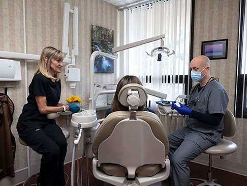 Dental team member and dentist treating dentistry patient in modern dental office