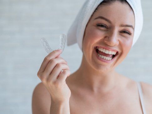 Smiling woman holding a nightguard for bruxism