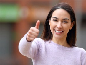Woman in sweater giving thumbs up for cosmetic treatment