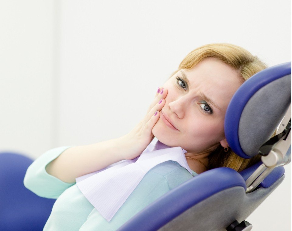 Woman in need of emergency dentistry holding cheek in pain