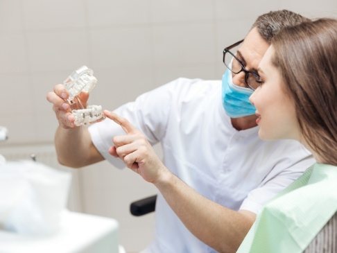 Dentist using smile model to show how he treats dental emergencies