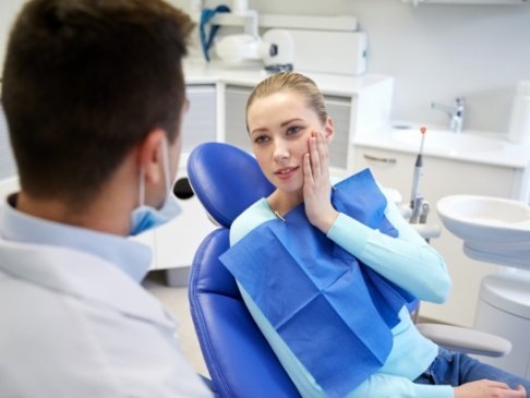 Woman in need of emergency dentistry holding cheek in pain