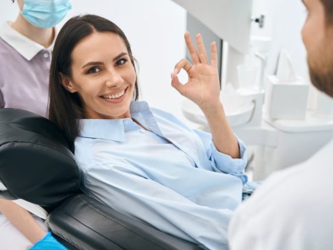 a patient giving the okay sign after a dental visit