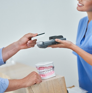A patient using a credit card to pay the cost of dental implants