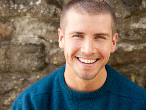 Man in front of stone wall smiling with dental implants in Ledgewood, NJ