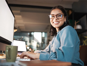 Woman sitting at desk smiling with dental implants in Ledgewood, NJ