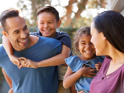 Family of four smiling outdoors on sunny day