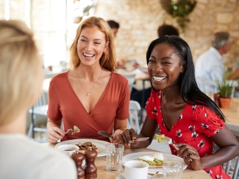 Two women laughing and sitting next to each other at restaurant table