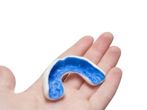 Patient holding blue and white mouthguard