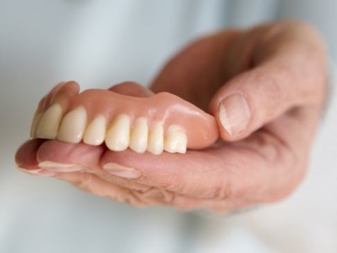 Hand holding a full denture