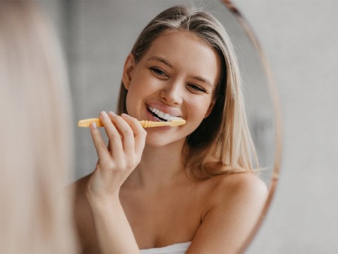 Woman smiling while brushing her teeth