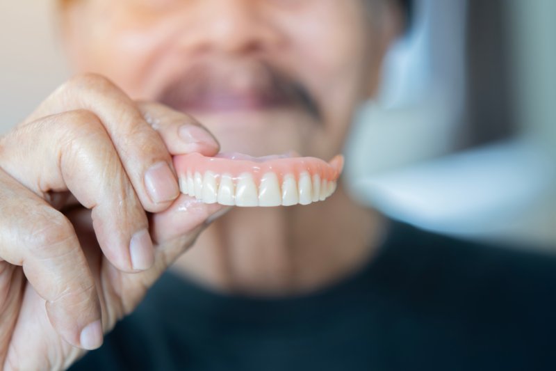 Patient smiling with their new denture after dental emergency