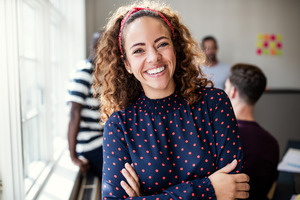 Woman in polka dot shirt smiling with arms folded